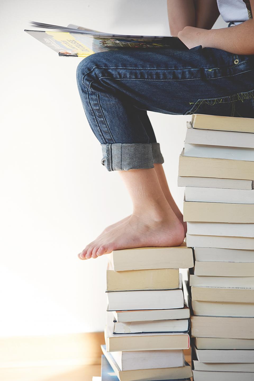 Student reading on a stack of books